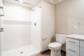 A white bathroom with a toilet, sink, and shower.